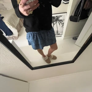 Blå kortkjol från Zara - Säljer en söt blå kortkjol från Zara med svart blommigt mönster. Kjolen har en elastisk midja som ger en bekväm passform. Perfekt för en avslappnad stil. Men inbyggda shorts💕