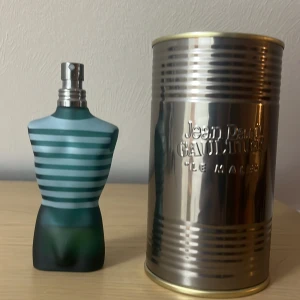Le Male Eau de Toilette från Jean Paul Gaultier - Säljer en ikonisk Le Male Eau de Toilette från Jean Paul Gaultier. Flaskan är formad som en manlig torso i blått och turkost med horisontella ränder. Den kommer i en unik metallförpackning som ger en industriell känsla. Perfekt för den som vill ha en klassisk och maskulin doft. Flaskan är en 75 ml men det innehåller cirka 15-20 ml 