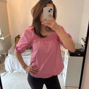 Rosa blus med puffärmar - Säljer en söt rosa blus med puffiga trekvartsärmar och en smockad halsringning. Perfekt för en avslappnad och stilren look. Passar bra till både jeans och kjol.