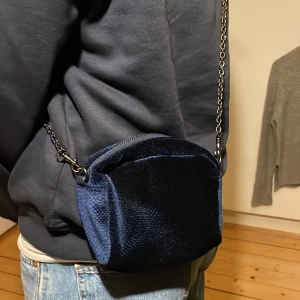 Mörkblå liten axelväska med kedja💙 - Snygg mörkblå axelväska med kedja och dragkedja Väskan är använda en gång och är i ny skick.  Väskan har en texturerad yta som ger den en unik look. Perfekt för att bära dina nödvändigheter med stil. Enkel och elegant design som passar till många tillfällen.