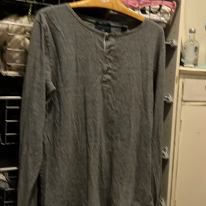 Grå långärmad tröja - Säljer en enkel och stilren grå långärmad tröja. Perfekt för en avslappnad look. Tröjan har en rund halsringning och knappar framtill. Passar bra till både jeans och kjol.