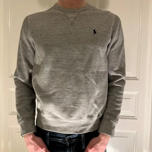 Polo Ralph Lauren crewneck  - Grå Ralph Lauren tröja i storleken M. Varan är sparsamt använd och i ett bra skick utan synliga defekter. Modell: 187 cm 80 kg