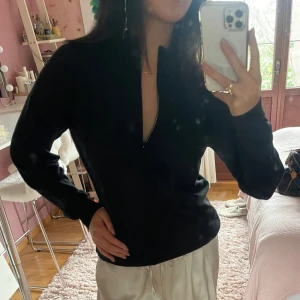 Svart långärmad tröja med dragkedja - Säljer en stilren svart långärmad tröja med dragkedja i halsen. Perfekt för en avslappnad och bekväm look. Passar bra till både jeans och mjukisbyxor.