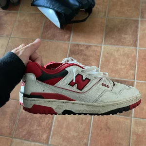 New Balance 550 i röd och vit - Säljer ett par New Balance 550 sneakers i röd och vit färg. Skorna har en klassisk design med snörning och en robust sula. Perfekta för en sportig look. Strl 40.5 passar 41. Knappt använda