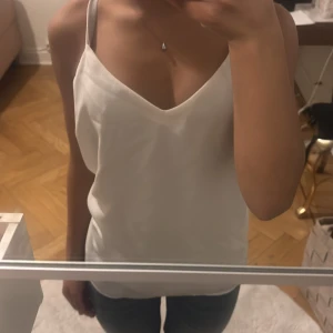 Vit ärmlös linnetopp - Säljer en stilren vit linnetopp med smala axelband och v-ringning. Säljer då den tyvärr är för stor.💕 