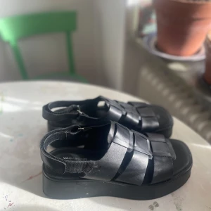 Svarta sandaler i skinn från Vagabond - Snygga svarta skinnskor från Vagabond i storlek 40, aldrig använda. De har en robust plattå och breda remmar som ger en bekväm passform. Perfekta för en stilren look i vår och sommar. Nypris 1600kr.