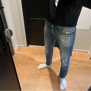 Blå Dondup jeans med slitningar - Snygga blå jeans med slitningar och en klassisk femficksdesign. De har en normal passform och är perfekta för en avslappnad stil. Jeansen har en dragkedja och knapp framtill. Hör av er i dm för frågor jeansen är inte så använda och i bra skick