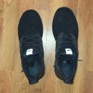 Svarta Adidas Ultraboost sneakers - Säljer ett par svarta Adidas Ultraboost sneakers. Skorna har en stickad ovandel och en bekväm Boost-sula. Perfekta för både träning och vardag. De har klassisk snörning och en stilren design.