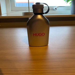 Parfym från Hugo Boss - Säljer en stilren parfym från Hugo Boss i en silverfärgad flaska med röd logotyp. Flaskan har en praktisk skruvkork med en svart rem. Perfekt för den som vill ha en klassisk och tidlös doft. Använd väldigt lite.