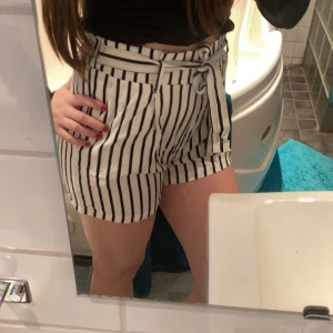 Randiga shorts med knytband - Snygga vita shorts med svarta ränder och ett knytband i midjan. Perfekta för en somrig look. De är högmidjade och har en avslappnad passform som ger en skön känsla. Passar bra till både t-shirt och blus.❤️