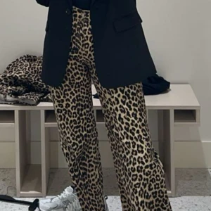 Leopardmönstrade byxor från H&M - Snygga leopardmönstrade byxor från H&M i storlek 36. Byxorna har en rak/wide passform med knapp och dragkedja framtill. Perfekta leopardbyxorna byxorna köptes för 399kr säljer för 200kr de är endast använda 2 gånger. De är slutsålda på hm 