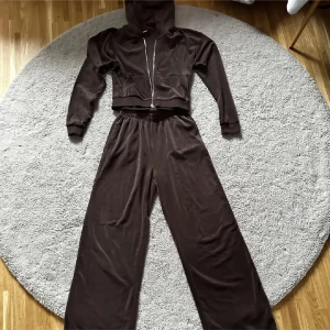 Brun hoodie och byxor set - Säljer ett brunt set med kort kofta och byxor, perfekt för en avslappnad stil. Byxorna har en bekväm passform med resår i midjan. Byxorna i xs och koftan i S. Dem är ganska långa på mig som är 165cm så dem kan släpas bakom en, men det finns inga defekter. Vid ytterligare bilder och frågor skriv!