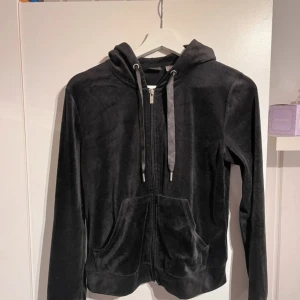 Svart huvtröja  - Säljer en svart huvtröja från Gina Tricot i mjukt material. Den har dragkedja framtill och en justerbar huva med snören. 