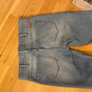 Blå bootcut jeans - Snygga blå bootcut jeans med hög midja och klassiska bakfickor. Jeansen har en lätt slitning framtill och stängs med dragkedja och knapp. Perfekta för en avslappnad stil. 🩷 De va för små när jag köpte dom så har därför inga bilder på! 