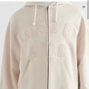 Beige hoodie med dragkedja från Axel Arigato - Snygg beige hoodie från Axel Arigato med dragkedja och textdetalj framtill. Skriv för egna bilder! (Lite slitningar runt texten) 