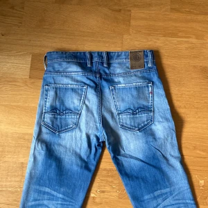 Blå jeans från Replay - Et par riktigt snygga replays jeans med snygga slitningar i en ljusblå/washed colorway. Storleken är 29/30. Slitningar förekommer framförallt på fickorna vid baksidan och på vänstra låret (se bilder). Hör av er vid frågor eller liknande! Priset är inte spikat i sten!