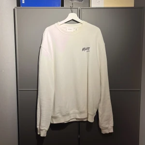 Vit sweatshirt från Axel Arigato - Säljer en stilren vit sweatshirt från Axel Arigato. Tröjan är tillverkad i ekologisk bomull och har en enkel design med rund hals och långa ärmar. Perfekt för en avslappnad look. Den är i storlek xl, använd flera gånger men hängt i garderoben i ett halvår ungefär, den är ganska oversize 