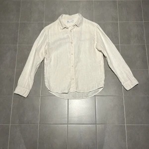 Beige linneskjorta från Arket - Snygg och stilren beige skjorta från Zara i 100% linne. Perfekt för en avslappnad men ändå elegant look. Skjortan har långa ärmar och knappar framtill. Passar utmärkt till både alla sorters plagg. Barn storlek:11-12 år (152cm)