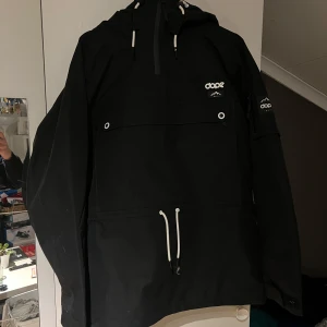 Svart skid/snowboardjacka DOPE - Endast använd under en veckas skidåkning. Mycket väl omhändertagen under veckan samt efter, så den har inga defekter jag är medveten om.  Storlek M, men lite oversize. Fickor på sidorna och i fram samt ficka på ärmen för liftkort. Dragkedjeöppningar under ärmarna för ventilation.