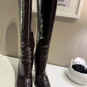 Svarta lackstövlar med klack - Snygga mörkbruna stövlar med hög klack och spetsig tå. Perfekta för en elegant look. Klackhöjd 10,5 cm Dem är jätte sköna att gå med. Köpta på Zalando i november 2024.