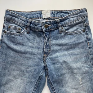 Blå jeans - Snygga blå lågmidjade vintage jeans med raka ben. De har en ljus tvätt och har snygga slitningsdetaljer på låret. Passar bra till allt! 