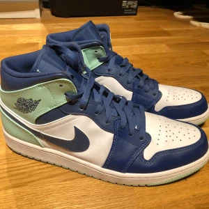 Nike Air Jordans i blått och vitt - Snygga Nike Air Jordans i en fräsch kombination av blått, vitt och mintgrönt. Skorna har klassisk snörning och den ikoniska Air Jordan-loggan på sidan. Perfekta för dig som vill ha stil och komfort i ett. Skorna har använts en gång och är i strl 46.