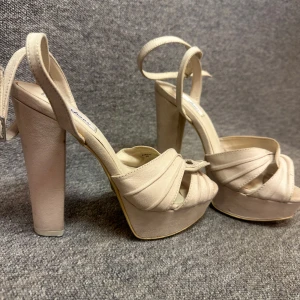 Beige klackskor från NLY Shoes - Snygga beige klackskor från NLY Shoes med hög platå och knytband runt ankeln. Skorna har en elegant design med korsade remmar framtill och en stabil blockklack.