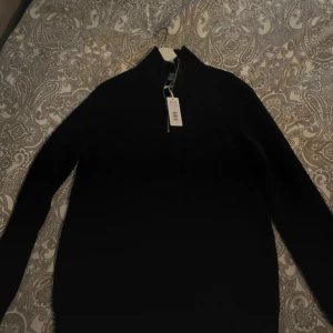 Mörkblå tröja med halv dragkedja från Brothers - Säljer en stilren mörkblå tröja från Brothers med halv dragkedja. Perfekt för kyligare dagar och ger en snygg look. Tröjan har långa ärmar och en hög krage.