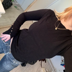 Svart långärmad tröja med knappar - Snygg svart långärmad tröja med knappar vid ärmsluten. Passar mig med S