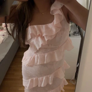 Ljusrosa klänning med volanger från Boohoo - Säljer en söt ljusrosa klänning från Boohoo med volanger och ett gulligt blommönster. Klänningen har en oneshoulder-design och är perfekt för exempelvis bal. Den har bara testats på och är helt oanvänd och har till och med prislappen kvar. Jag säljer för att den är för liten på mig tyvärr. Boohoo har små storlekar och även om klänningen är i 38 skulle den passa 36, dvs storlek S <3 Orginal pris var 995kr