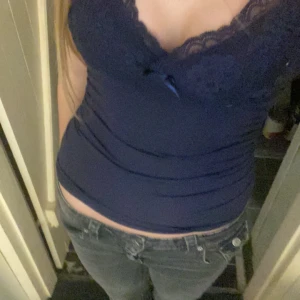 Mörkblå spetslinne - Snygg mörkblå linne med spetsdetaljer och en liten rosett framtill. Säljer för att det inte är min stil! 