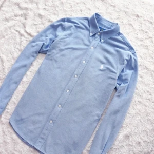 Ralph Lauren Skjorta - “Hej! Säljer en klassisk Ralph Lauren-skjorta i storlek Medium. Ljusblå med broderad logotyp. Skjortan är i utmärkt skick, utan tecken på användning. Perfekt för både vardag och fest. Hör av dig vid eventuella frågor!”