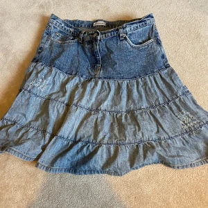 Jeanskjol från Clockhouse - Säljer en jeanskjol från Clockhouse med volangdetaljer. Kjolen har en avslappnad passform och är perfekt för en casual look. Den är i en klassisk blå denimfärg och har fickor både fram och bak 💞