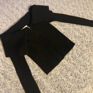 Svart tröja/kofta från Bershka - Säljer en stilren svart ribbad tröja från Bershka. Tröjan har långa ärmar och en modern design som passar perfekt till olika outfits. Perfekt för dig som vill ha något enkelt men snyggt i garderoben. Jätte snygg att ha off shoulder 