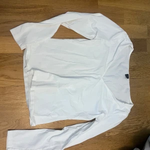 Vit långärmad topp - Säljer en stilren vit långärmad topp. Perfekt för lager-på-lager eller att bära som den är. Enkel och mångsidig design.