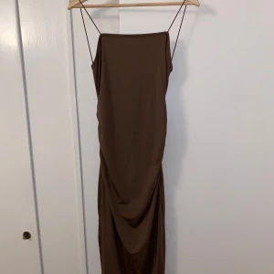 Brun klänning med tunna band - Elegant brun långklänning från shein med smala axelband och draperad detalj framtill. Slits vid sidan. Perfekt för fest eller cocktail party!