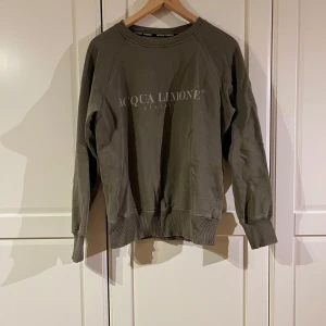 Olivgrön sweatshirt från Acqua Limone - Säljer en olivgrön sweatshirt från Acqua Limone med tryck på både fram- och baksidan. Tröjan har långa ärmar och ribbade muddar vid ärmslut och nederkant. Perfekt för en avslappnad stil.