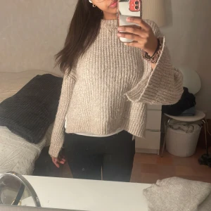 Beige stickad tröja - Nypris 699kr men säljs för 300kr. Mysig beige stickad tröja i ribbat material. Perfekt för kyliga dagar med sin avslappnade passform och långa ärmar. Den har en klassisk rund hals och är superbekväm att bära. Passar perfekt till både jeans och leggings!