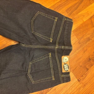 Mörkblå jeans från Cheap Monday - Snygga mörkblå jeans från Cheap Monday med klassisk femficksdesign och kontrasterande sömmar som är i en orange/gul nyans. Passar en S och är mycket långa i benen.