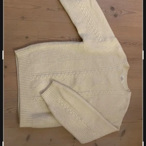 Beige stickad tröja - Säljer en mysig beige stickad tröja med kabelstickat mönster. Tröjan har långa ärmar och en rund halsringning. Perfekt för kyliga dagar! Storlek 158/164