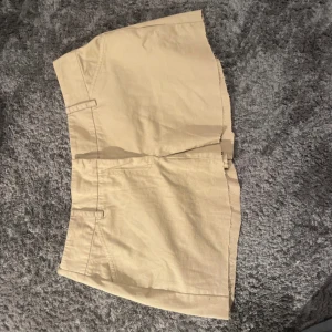 Beige kjol - Säljer en snygg beige kjol i bomull. Den har en klassisk design med fickor och är perfekta för sommardagar. Passar till både vardag och festliga tillfällen. Skön och lät att matcha med olika toppar!