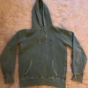 Grön hoodie från Polo Ralph Lauren - Säljer en snygg grön hoodie från Polo Ralph Lauren. Den har en klassisk design med en känguruficka och justerbar huva. Perfekt för en avslappnad stil.