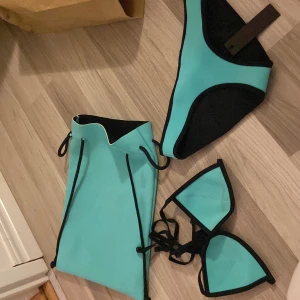 Turkos bikini från Triangl - Säljer en snygg turkos bikini från Triangl i neoprenmaterial. Den har svarta kanter och knytband för en justerbar passform. Perfekt för sommarens stranddagar! 🏖️underdelen är helt oanvänd, medans överdelen är använd 2-3 gånger 💕Priset kan diskuteras vid snabb affär❗️‼️