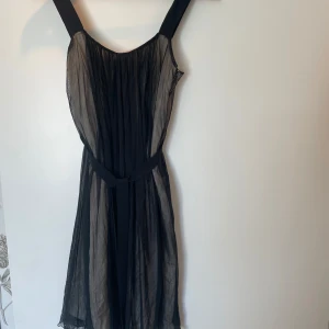 Svart festklänning från Reiss - Elegant svart klänning från Reiss i ett transparent material med ett fint fall. Ner till knät på mig som är 1,68. Klänningen har breda axelband och en dragkedja i sidan för enkel påklädning. Perfekt för festliga tillfällen!