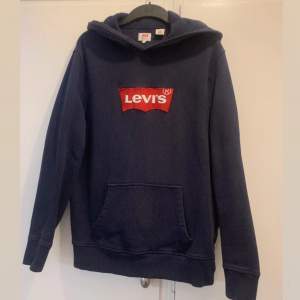 Säljer en snygg mörkblå hoodie från Levi's med den klassiska röda logotypen på bröstet. I storlek L/M  