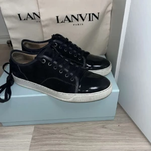 Svarta sneakers från Lanvin - Snygga svarta sneakers från Lanvin med snörning och vit sula. Perfekta för en stilren look. 