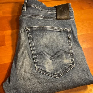 Blå jeans från Replay - Snygga blå jeans från Replay med en klassisk femficksdesign. De har en lätt tvättad look och en diskret Replay-logga vid fickan. Perfekta för en avslappnad stil. W30 L32. Modell: GROVER.