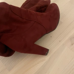 Röda mockastövlar med klack - Snygga röda stövlar i mocka med klack. Perfekta för att ge en färgklick till din outfit. De har en elegant design som passar bra till både vardag och fest.