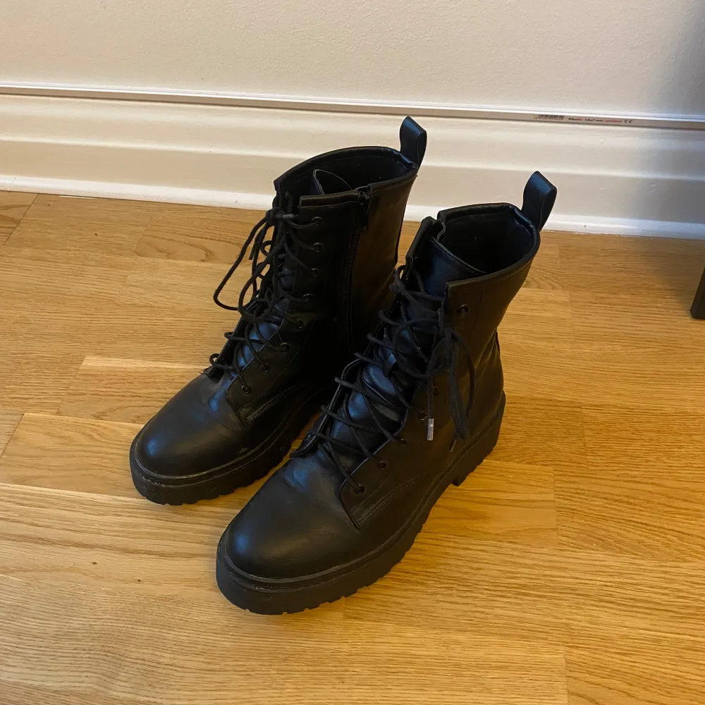 Säljer ett par snygga svarta boots i skinn med snörning framtill. De har en robust sula och är perfekta för höst och vinter. Bootsens stilrena design gör dem lätta att matcha med olika outfits. De är i mycket bra skick och redo för nya äventyr!. Skor.