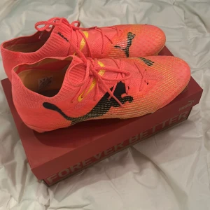  fotbollsskor från Puma - Säljer ett par rosa fotbollsskor från Puma med svart logotyp och gula detaljer. Strl 41. Är bara testade 1 träning